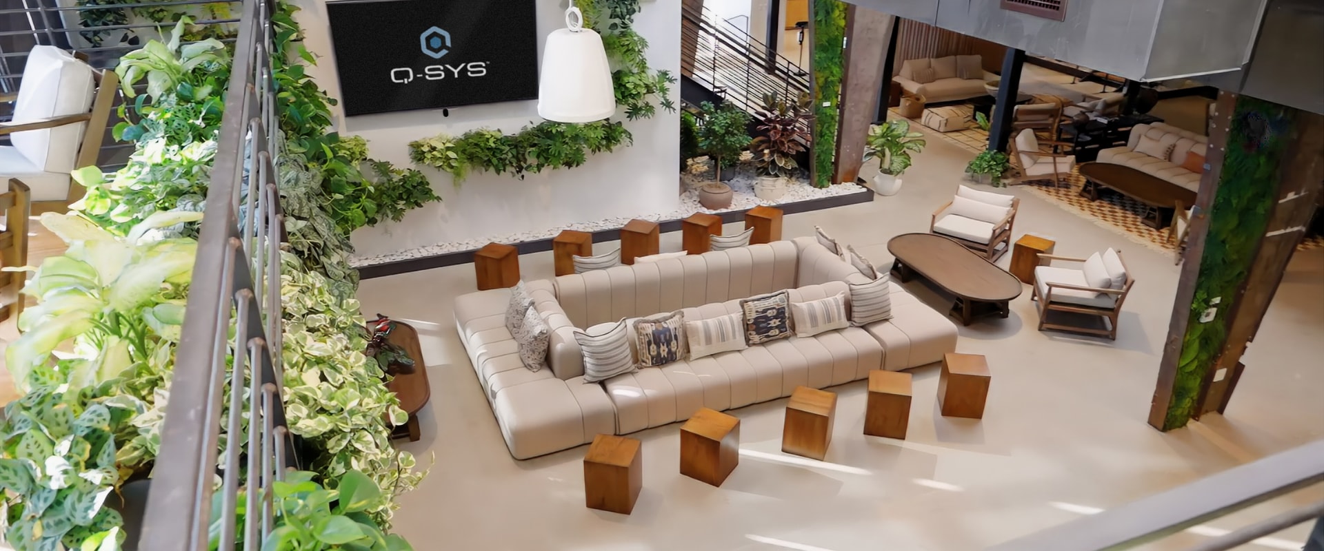 Inviting lounge area with natural elements, featuring Q-SYS branding and comfortable seating arrangements.